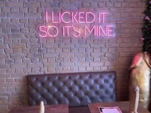 Pink neon sign displayed against a brick wall inside Naked Soho restaurant.